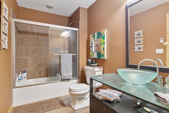 bathroom featuring shower / bath combination with glass door, tile patterned flooring, vanity, and toilet