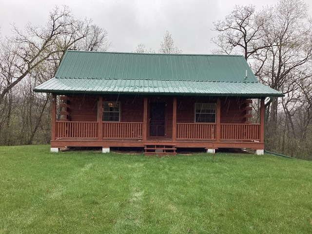 view of front of house with a porch, log exterior, metal roof, and a front yard