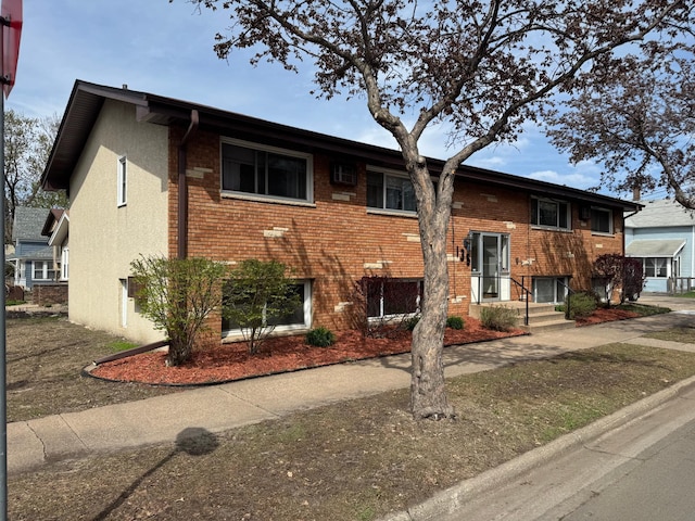 split foyer home featuring brick siding and stucco siding