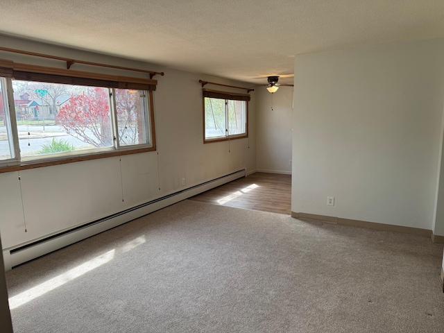 unfurnished room with light carpet, baseboard heating, a textured ceiling, a ceiling fan, and baseboards