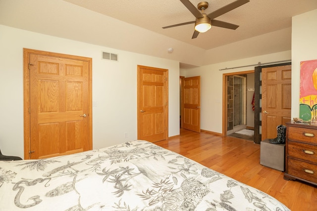 bedroom featuring light wood-style flooring, a ceiling fan, and visible vents