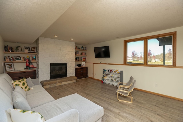 living room with a textured ceiling, baseboards, and wood finished floors