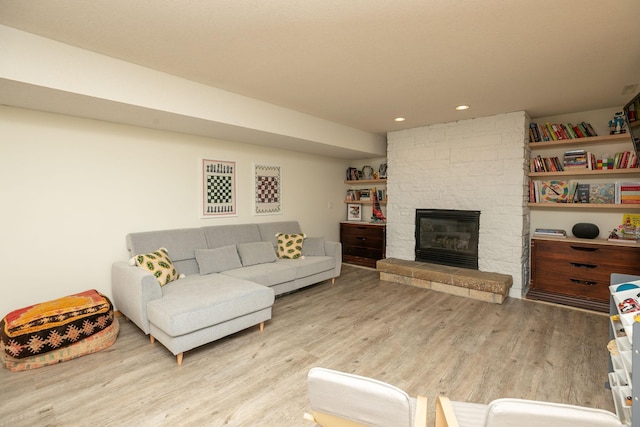 living area featuring recessed lighting, a stone fireplace, and wood finished floors