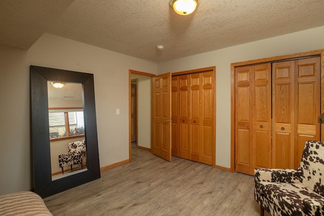 sitting room featuring baseboards, light wood-style floors, and a textured ceiling