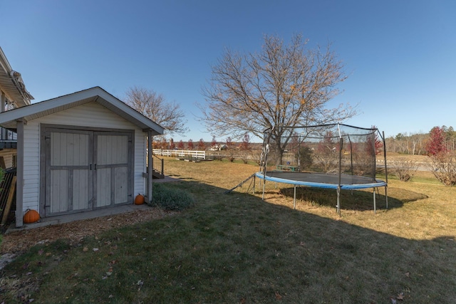 view of yard featuring a trampoline, an outdoor structure, and a storage shed