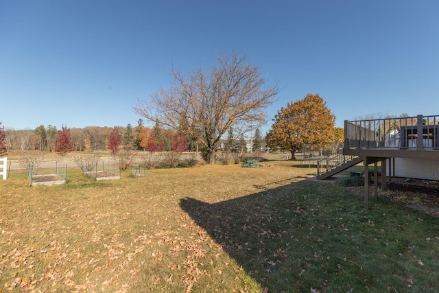 view of yard with fence, stairs, a trampoline, a deck, and a garden