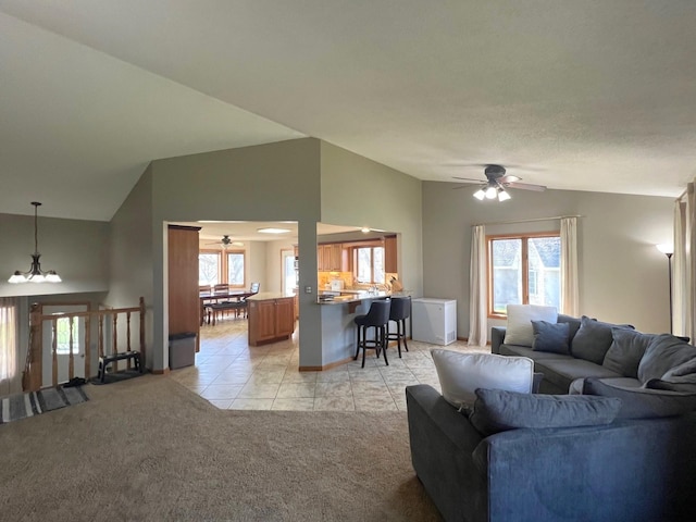 living area featuring ceiling fan, light colored carpet, lofted ceiling, light tile patterned floors, and a chandelier