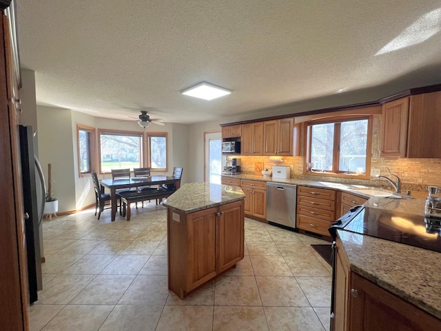 kitchen with appliances with stainless steel finishes, a sink, plenty of natural light, backsplash, and a textured ceiling