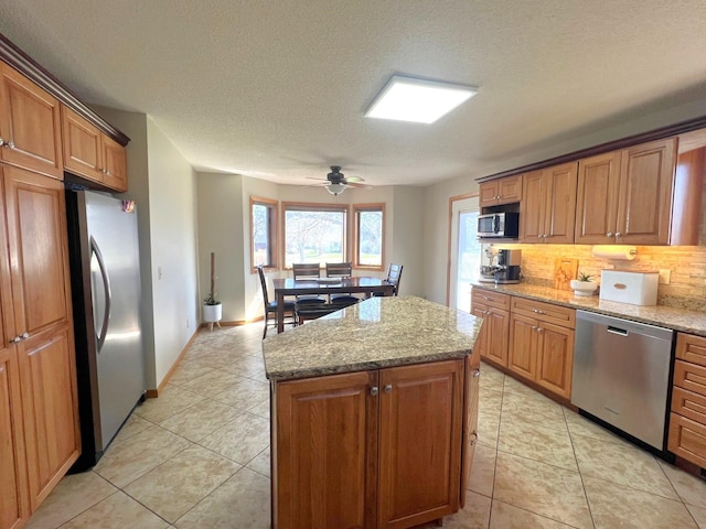 kitchen featuring stainless steel appliances, tasteful backsplash, a center island, ceiling fan, and a textured ceiling