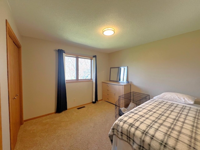 bedroom with light colored carpet, a textured ceiling, baseboards, and a closet