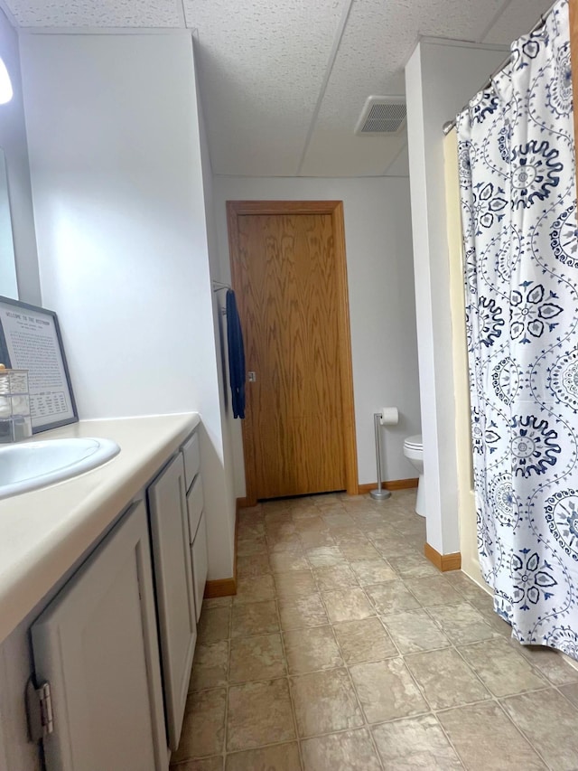 full bath with toilet, baseboards, vanity, and curtained shower