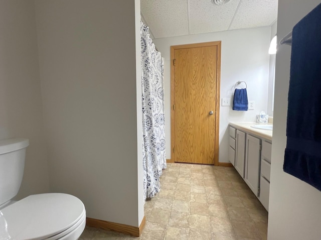 full bathroom with toilet, baseboards, vanity, a shower with shower curtain, and a drop ceiling