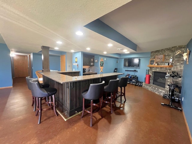 indoor wet bar featuring a fireplace, recessed lighting, a textured ceiling, and baseboards