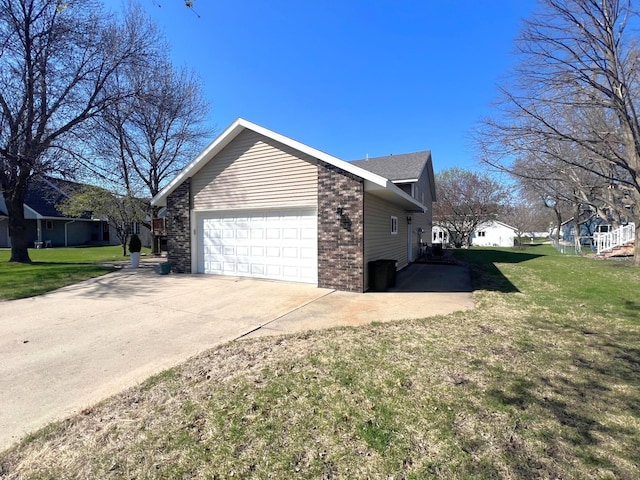 view of property exterior with an attached garage, concrete driveway, brick siding, and a yard