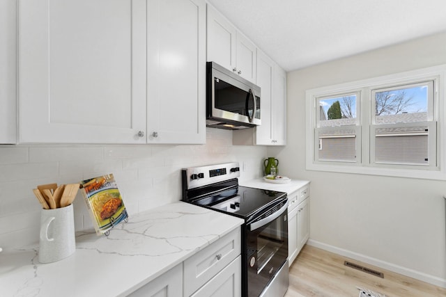 304 Lakeview Ave, Long Lake, MN 55356 - kitchen featuring baseboards, light wood finished floors, white cabinetry, tasteful backsplash, and appliances with stainless steel finishes
