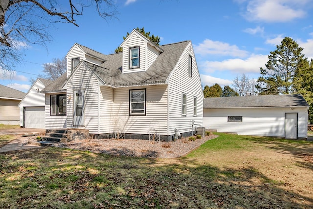 back of house featuring a yard, a shingled roof, an outdoor structure, and central air condition unit