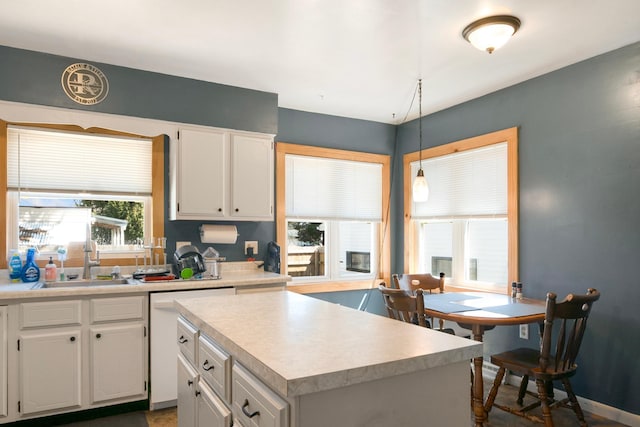 kitchen featuring a sink, light countertops, a center island, white cabinetry, and pendant lighting