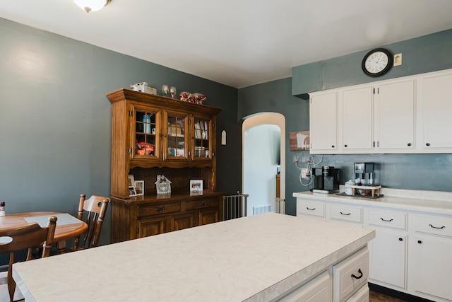 kitchen featuring light countertops, arched walkways, and white cabinetry