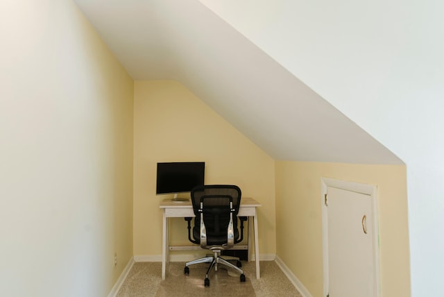 office space with baseboards, vaulted ceiling, and light carpet