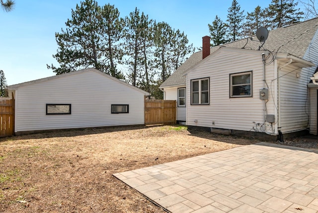 back of house featuring a shingled roof, a patio area, fence, and a chimney