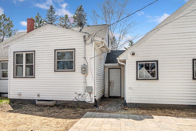 back of property with roof with shingles and a chimney
