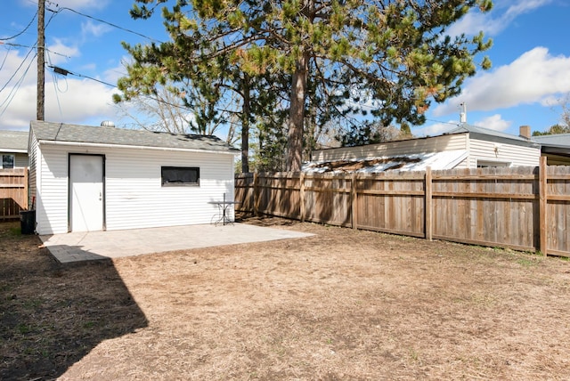 view of yard with a patio, a fenced backyard, and an outbuilding