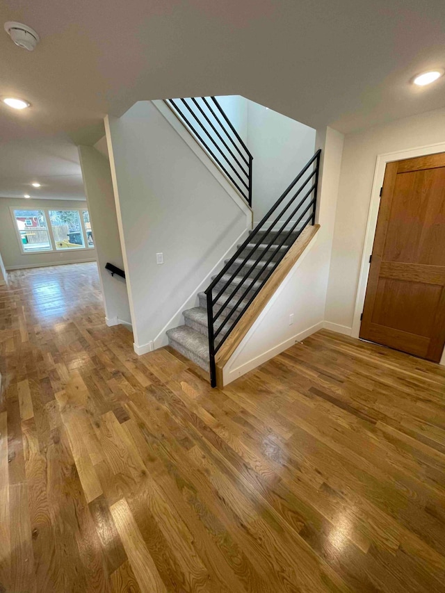 stairs with baseboards, recessed lighting, and wood finished floors