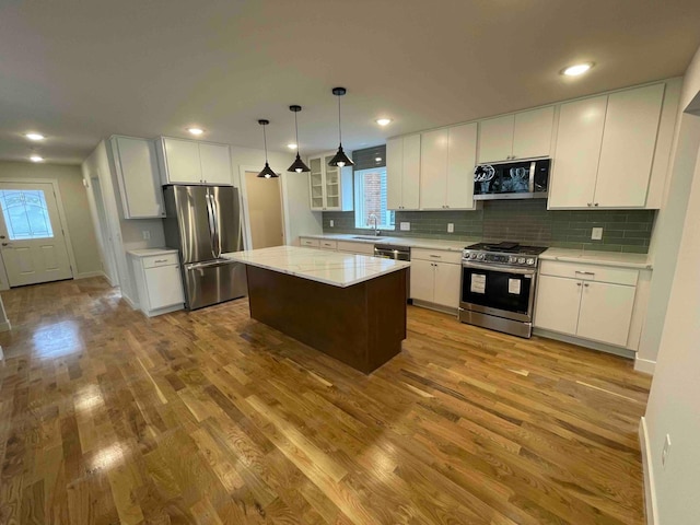 kitchen featuring decorative backsplash, stainless steel appliances, wood finished floors, and white cabinetry