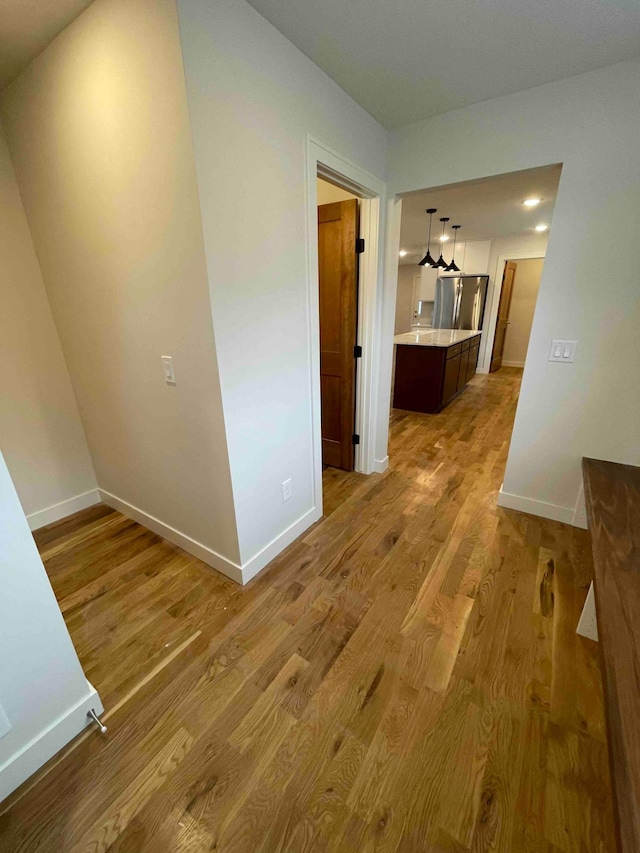 corridor featuring baseboards and wood finished floors