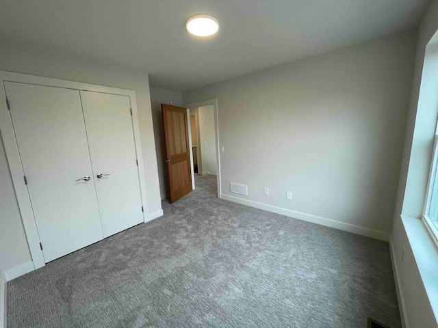 unfurnished bedroom with visible vents, carpet, baseboards, and a closet