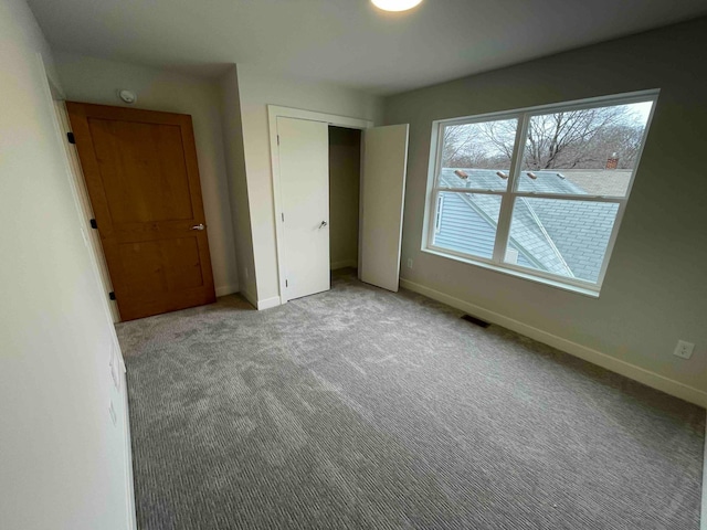 unfurnished bedroom with a closet, baseboards, carpet flooring, and visible vents