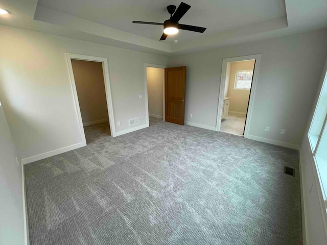 unfurnished bedroom with a raised ceiling, a spacious closet, and visible vents