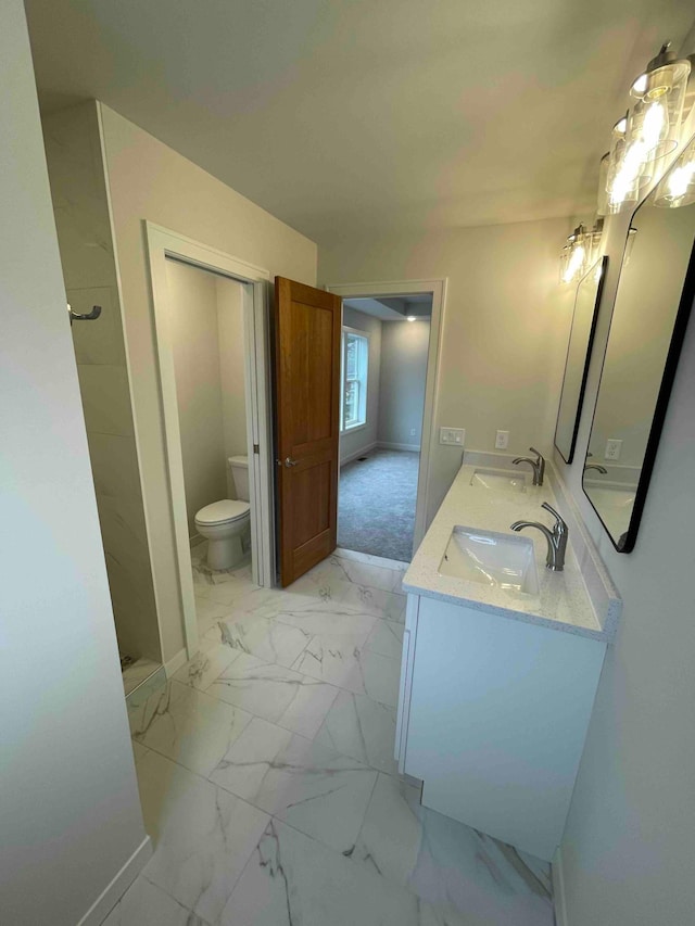 bathroom with double vanity, a sink, marble finish floor, and toilet