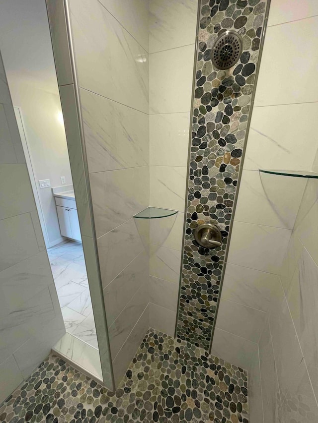 bathroom featuring tiled shower and marble finish floor