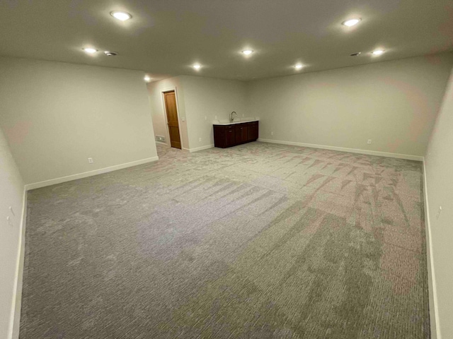 below grade area with recessed lighting, wet bar, light colored carpet, and baseboards