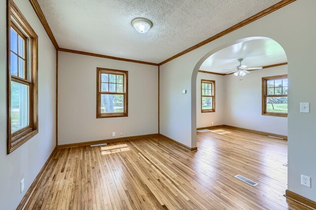 5159 Fawn Lake Dr NE, Linwood Twp, MN 55079 - unfurnished room featuring arched walkways, light wood-style flooring, crown molding, baseboards, and a textured ceiling