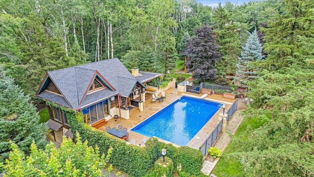 view of swimming pool with a fenced backyard, a fenced in pool, and a forest view