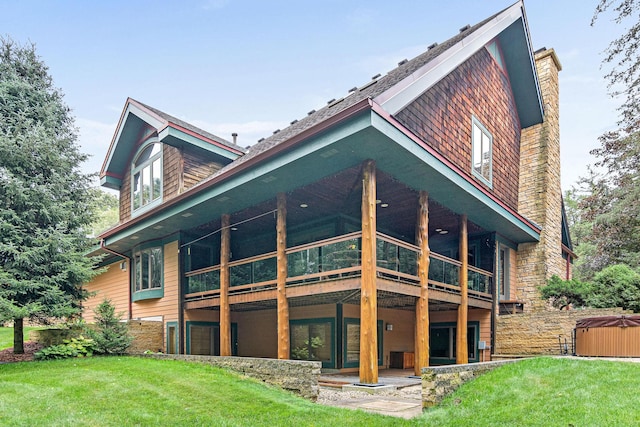 back of house featuring a lawn, a hot tub, a wooden deck, and a chimney