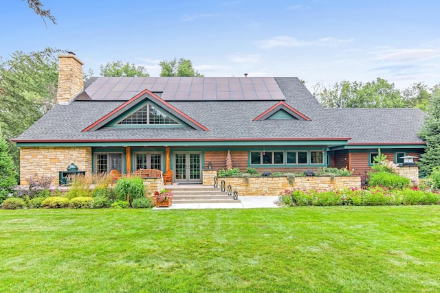 view of front of home with roof mounted solar panels, french doors, and a front yard