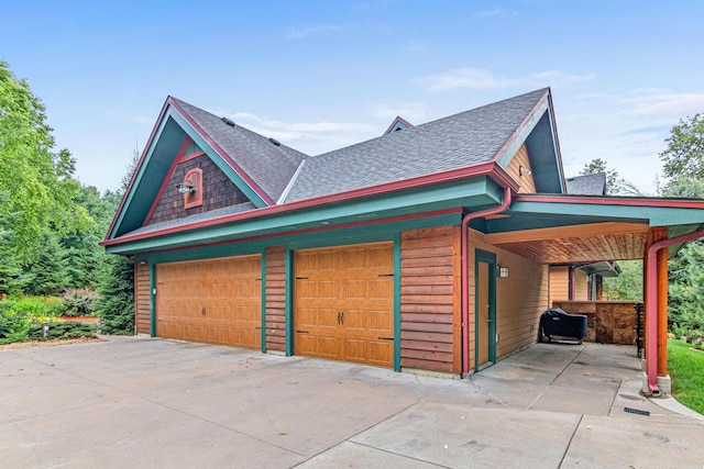 view of side of home featuring a shingled roof and driveway