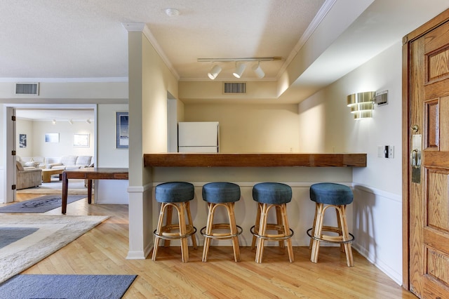 4387 Wilshire Blvd Unit 202, Mound, MN 55364 - kitchen featuring freestanding refrigerator, track lighting, ornamental molding, hardwood / wood-style flooring, and a breakfast bar area