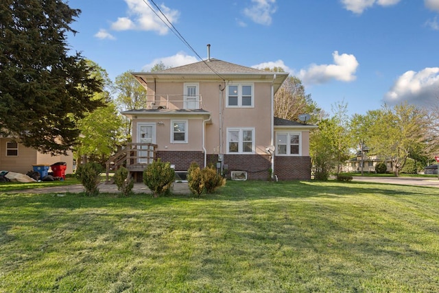205 2nd St SW, Blooming Prairie, MN 55917 - rear view of house with a balcony, stucco siding, a yard, and brick siding
