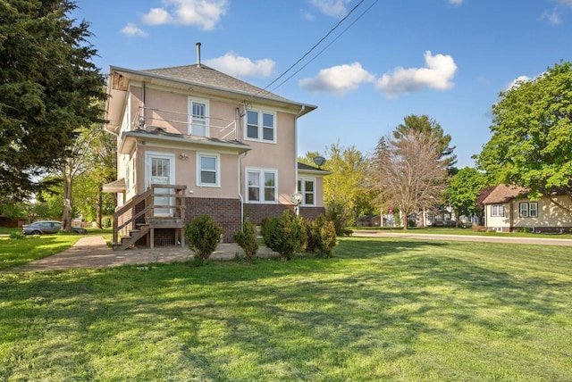 205 2nd St SW, Blooming Prairie, MN 55917 - rear view of property with stucco siding, a balcony, a lawn, and brick siding