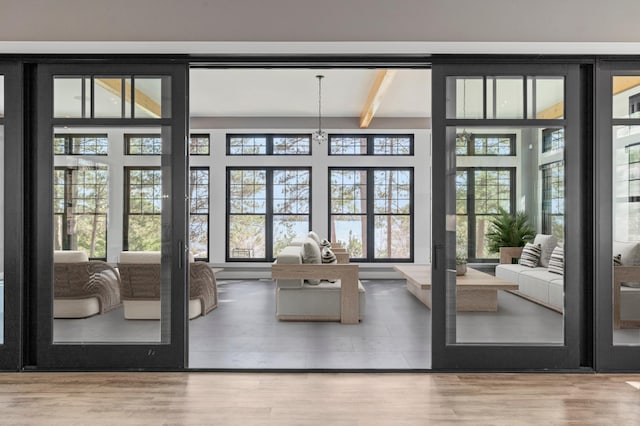 doorway with wood finished floors and beam ceiling