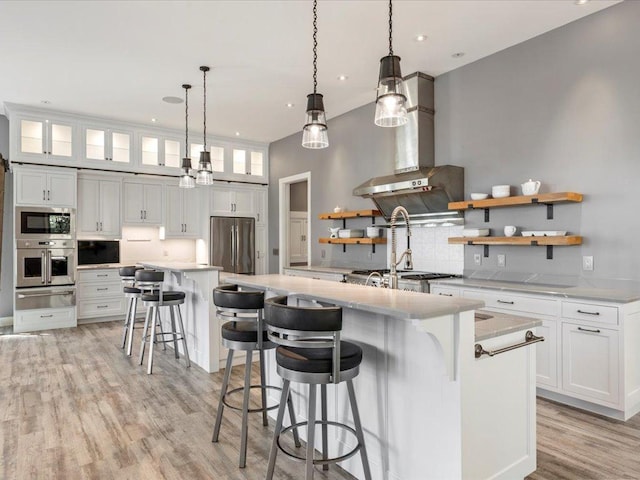 kitchen featuring stainless steel appliances, a warming drawer, a large island, backsplash, and light wood-type flooring