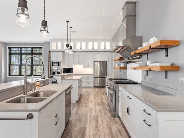 kitchen with open shelves, stainless steel appliances, a center island with sink, a sink, and white cabinetry