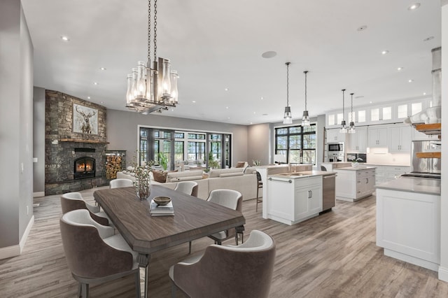 dining space with a chandelier, a fireplace, light wood-style floors, and recessed lighting