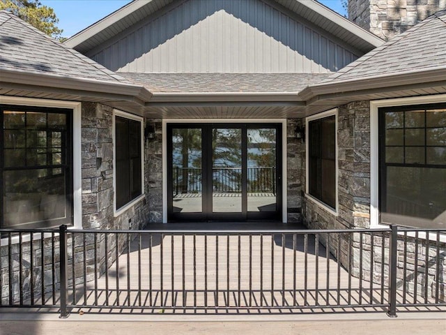 property entrance with stone siding, board and batten siding, and a shingled roof