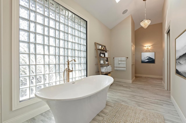 full bathroom featuring wood finished floors, a soaking tub, baseboards, and vaulted ceiling