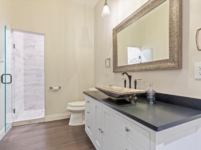 full bath with a shower stall, toilet, wood finished floors, baseboards, and vanity